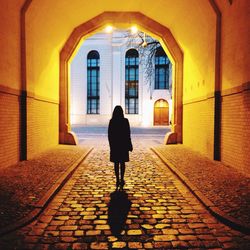 Rear view of silhouette woman standing in illuminated tunnel