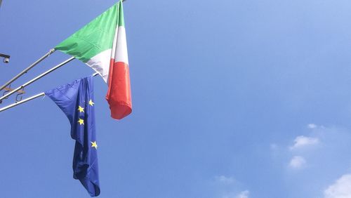 Low angle view of flags hanging against blue sky