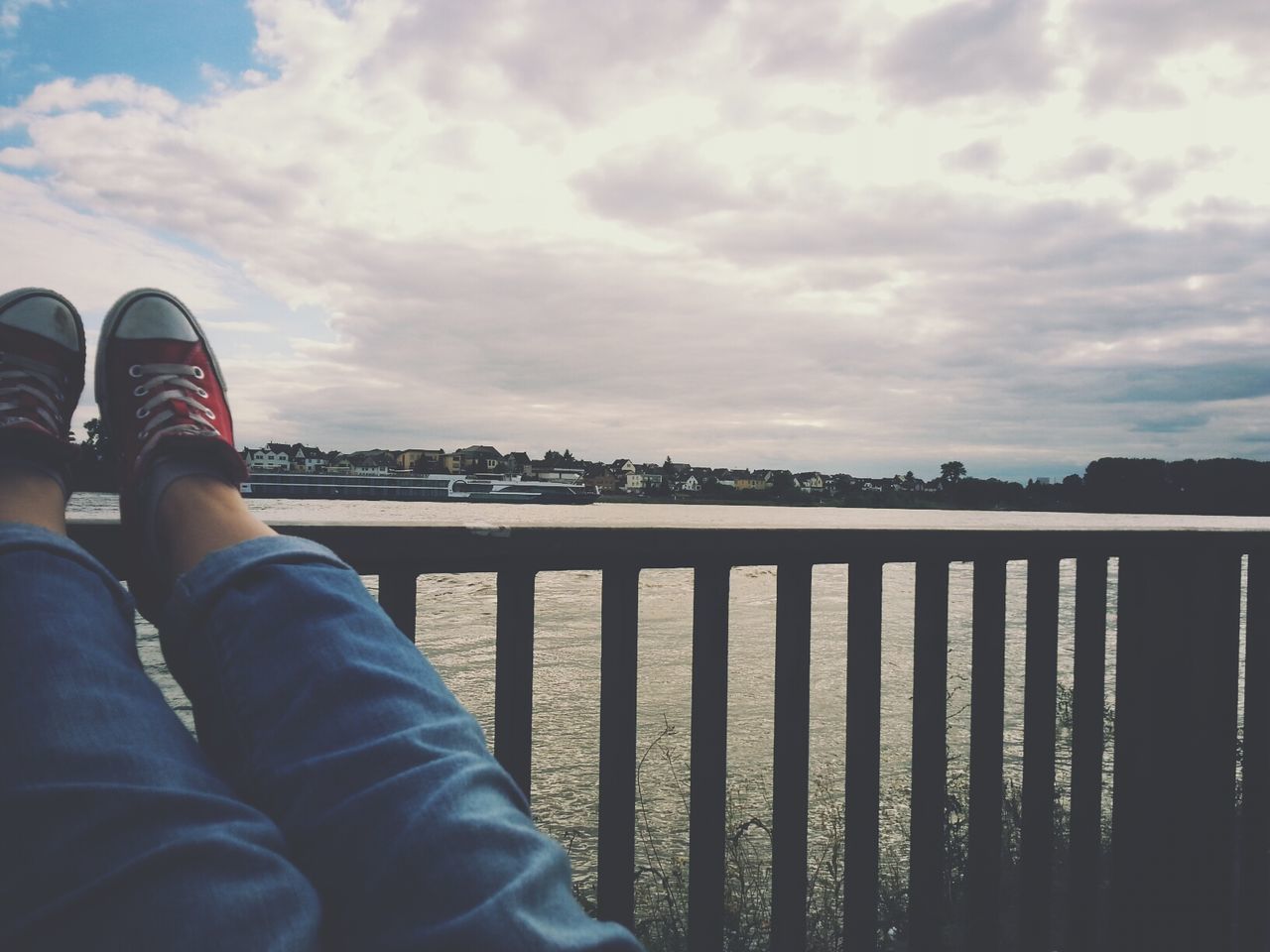 sky, cloud - sky, water, person, low section, personal perspective, lake, lifestyles, railing, river, cloud, men, cloudy, leisure activity, standing, shoe, unrecognizable person