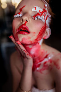 Close-up of woman in white and red face paint