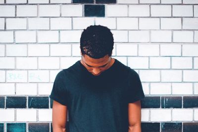 Man standing against brick wall