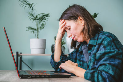 Tired and stressed woman sitting at her laptop and working from home