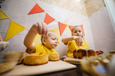 Children boy and girl prepare festive sweets decorate easter colored eggs on the table