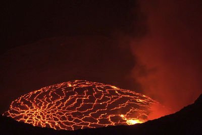 Firework display over mountain against sky at night