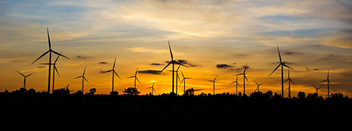 Silhouette cranes against sky during sunset