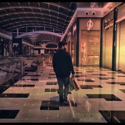 Rear view of man walking in illuminated building