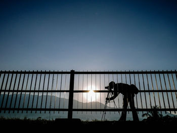 Silhouette man working against clear sky during sunset