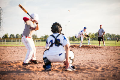 Rear view of boys playing on landscape against sky