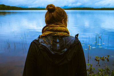 Rear view of woman standing by lake against sky