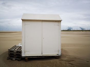 Lifeguard hut on sand at beach against sky