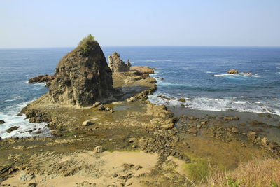 Rock formation on beach against clear sky