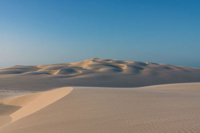 Scenic view of desert against clear blue sky