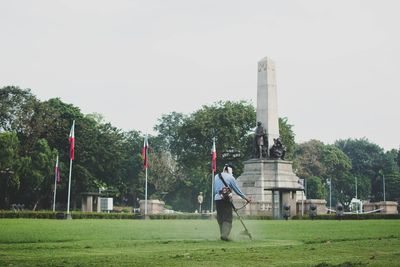 Man on golf course on field against sky