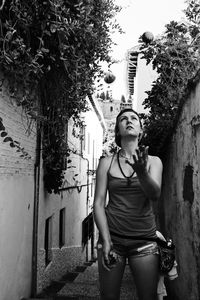 Woman juggling while standing in alley