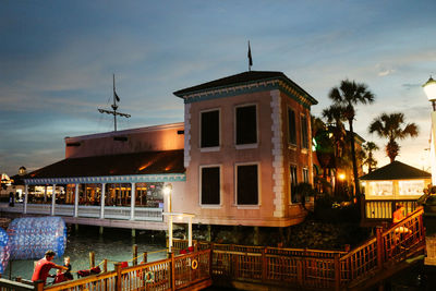 Building by illuminated city against sky at dusk