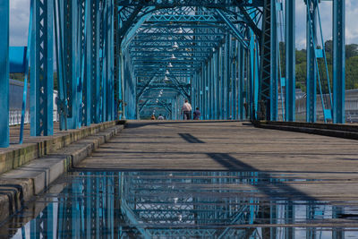 People walking on old steel foot  bridge over river