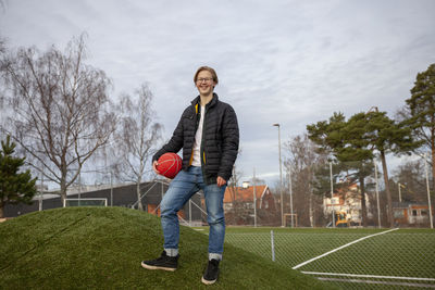 Portrait of smiling teenage boy holding basketball ball