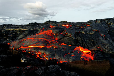 A lava flow emerges from a rock column and pours into a black volcanic landscape, hawaii, big island