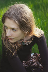 Close up woman looking away and sitting on grass portrait picture