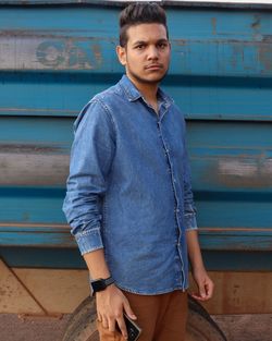 Portrait of young man standing against wall