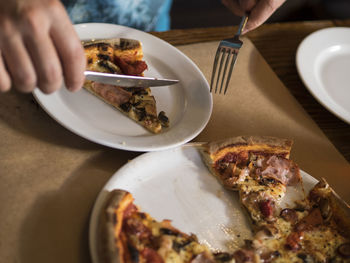 Close-up of person eating pizza in plate