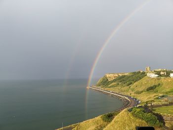 Scenic view of rainbow over sea against sky