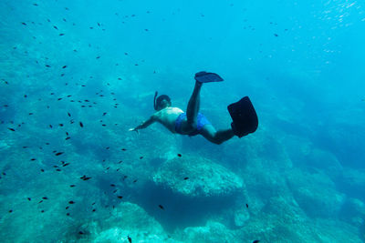 Shirtless young man scuba diving in sea