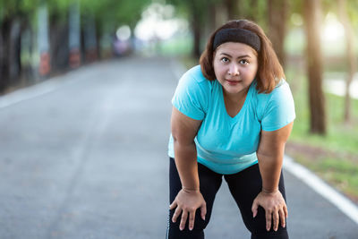 Portrait of tired woman bending on road