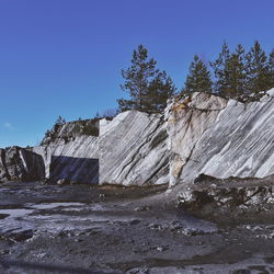 Rock formation amidst trees against clear blue sky