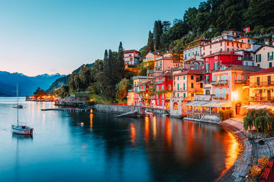 Buildings by river against clear sky