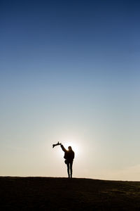 Silhouette woman standing on field against clear sky