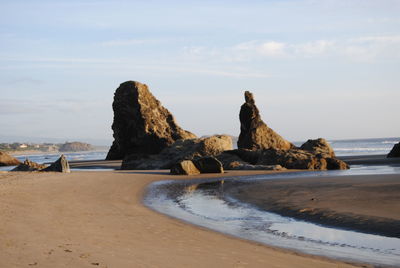 Rock formations on beach against sky