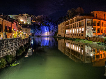 Illuminated bridge over river in city at night