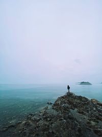 Figure and scenic view of sea and rocks against sky