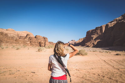 Rear view of woman with head in hand standing at desert