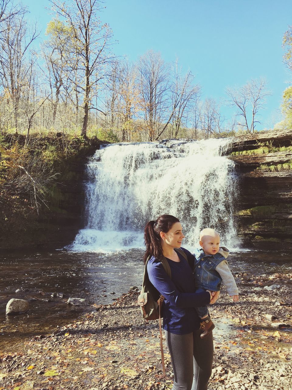 motion, water, standing, splashing, spraying, tree, side view, waterfall, fountain, clear sky, casual clothing, day, nature, person, embracing, scenics, beauty in nature, summer