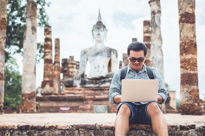 Asian tourist working and using laptop at sukhothai historical park, thailand