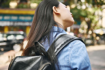 Woman with long hair carrying backpack in city