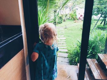 Rear view of girl standing amidst doorway at home