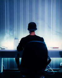 Rear view of a man sitting on table
