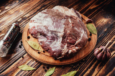 Close-up of raw meat with ingredients on wooden table