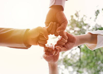 Midsection of couple holding hands against sky