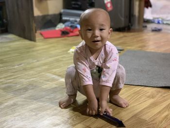 Portrait of cute girl sitting on hardwood floor at home
