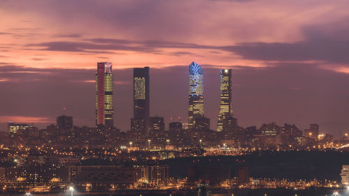 Illuminated modern buildings against sky at night