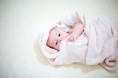 High angle portrait of baby boy lying on bed