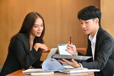 Young woman looking at camera while sitting on table