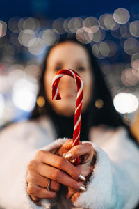 Female hand holding red white cane sweet lollipop. christmas holiday details