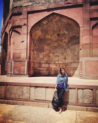 Full length of woman sitting outside building