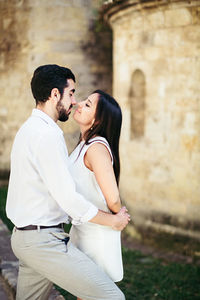 Couple romancing while standing against wall