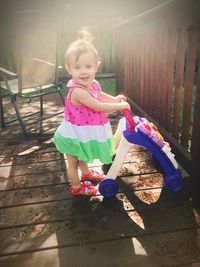 Full length of cute girl smiling while standing on wood